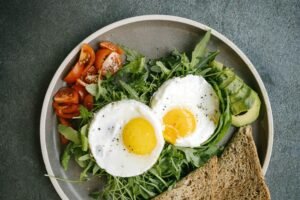 A delicious flat lay of a nutritious breakfast featuring eggs, avocado, and tomatoes.